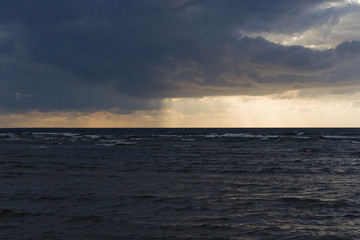 Fototapeta premium Rain clouds over Baltic sea near shoreline just before sunset, selective focus