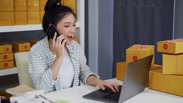 young woman talking on smartphone and use computer laptop to selling product online from home office