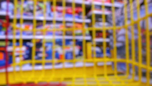 Trolley in the toy store, the subjective camera. Basket rides between rows of toys in the children's store. Make a purchase. Choose a gift for a child