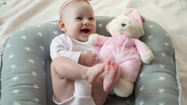 Portrait of little baby girl with toy bear ooks at camera and smiles.