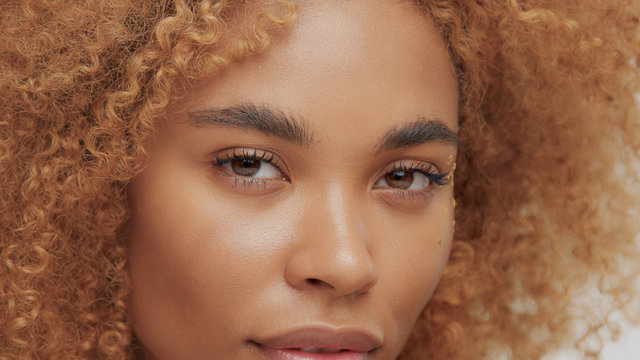 mixed race black blonde model with curly hair eyes closeup watching to the camera