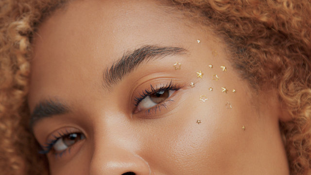 mixed race black blonde model with curly hair Woman face with golden stars makeup aplicated to ideal skin