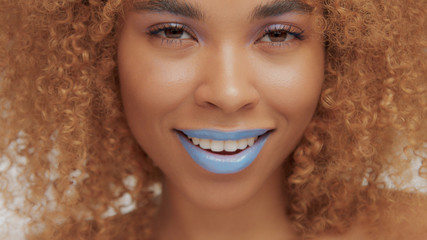 mixed race black blonde model with curly hair closeup of mouth painted with bright blue lipstick...