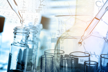 Dropping chemical liquid to test tube with lab glassware background. Science or chemistry research and development concept. 