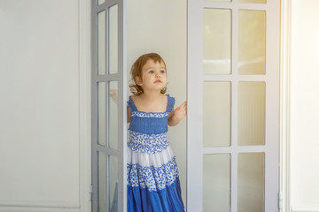 Little cute sweet smiling girl in blue dress dancing in bright light living room at home and laughing. Childhood, preschool, youth, relax concept