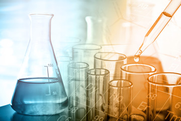 Dropping chemical liquid to test tube with lab glassware background. Science or chemistry research and development concept. 