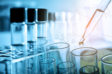 Dropping chemical liquid to test tube with lab glassware background. Science or chemistry research and development concept. 