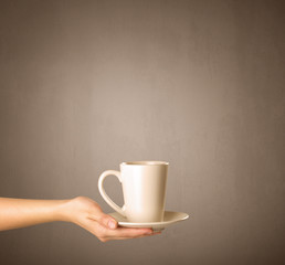 Young female hand holding tea mug with brown background