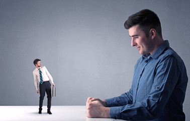 Young professional businessman being angry with an other miniature businessman 