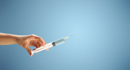 Female doctor hand holding syringe with blue background