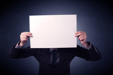 Young businessman hiding behind a blank piece of paper