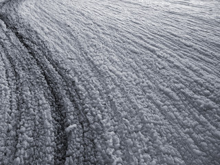 White wrinkled surface of foam made by water waves along a beach, close-up view. Beautiful black and white pattern of natural texture.