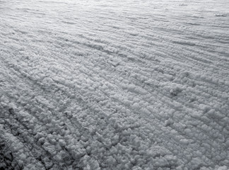 White wrinkled surface of foam made by water waves along a beach, close-up view. Beautiful black and white pattern of natural texture.