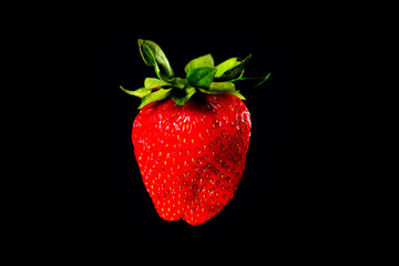 Strawberries on a black background with green leaves background close-up