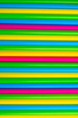 Colorful background. Vivid flatlay. Multicolored plastic drinking cocktail straws on a white background.