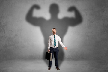 Fototapeta premium Lovely serious businessman standing with a muscular powerful shadow behind his back 