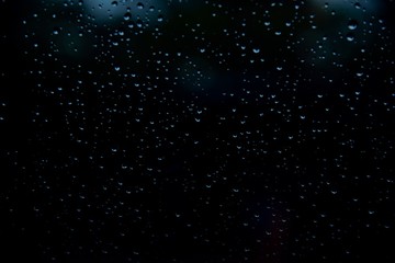 Obraz premium Drop water in glass on dark or black background