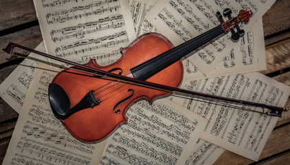 violin and bow on music sheet of paper