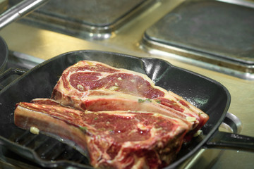 Raw fresh meat T-bone steak on grill iron pan