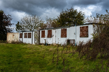 Fototapeta na wymiar Abandoned huts / cabins overgrown on an overcast day