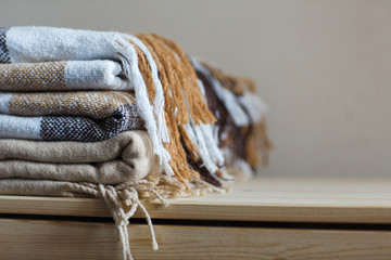home textile. stack of beige wool blankets on a wooden shelf.