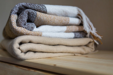 home textile. stack of beige wool blankets on a wooden shelf.