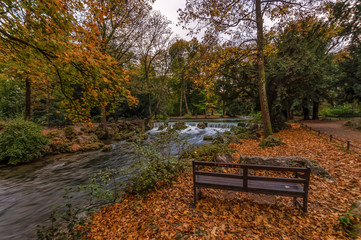 Ruhemoment im Herbst. Eine einsame Parkbank vor der Kulisse des Herbstes mit bunten Blättern,...