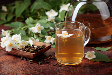Green tea with jasmine in cup and teapot .