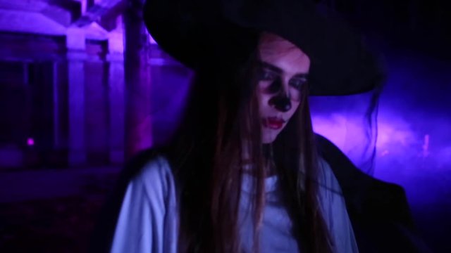 Woman with dead bride make-up for Halloween in the white bride dress in the dark at abandoned house