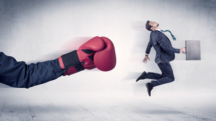 Huge Boxing Gloves punches innocent businessman concept

