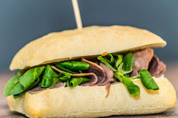 Fresh baguette sandwich on wooden background. Classic BLT sandwiches. Close up.