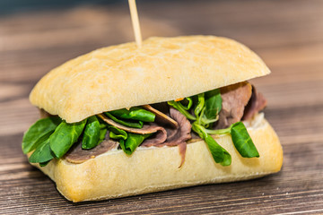 Fresh baguette sandwich on wooden background. Classic BLT sandwiches. Close up.