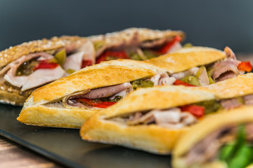 Fresh baguette sandwich on wooden background. Classic BLT sandwiches. Close up.