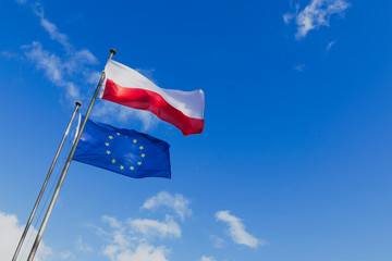 The Polish and European Union flags are waving in the wind. - obrazy, fototapety, plakaty