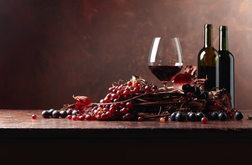 Obraz na płótnie Canvas Red wine and fresh grapes with dried up vine leaves.