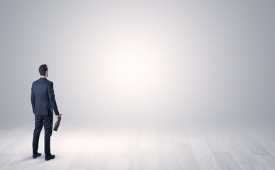 Man standing with his back in an empty room with object in his hand