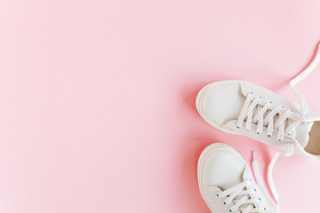 White female sneakers on pink background. Flat lay, top view minimal background. Fashion blog or magazine concept.