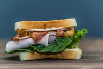 Fresh baguette sandwich on wooden background. Classic BLT sandwiches. Close up.