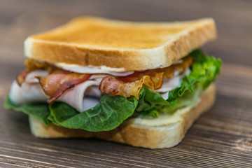 Fresh baguette sandwich on wooden background. Classic BLT sandwiches. Close up.