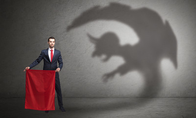 Businessman standing with red cloth in his hand and imp shadow on the background
