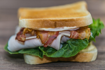 Fresh baguette sandwich on wooden background. Classic BLT sandwiches. Close up.