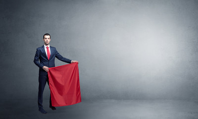 Businessman standing with red toreador cloth in his hand in an empty room
