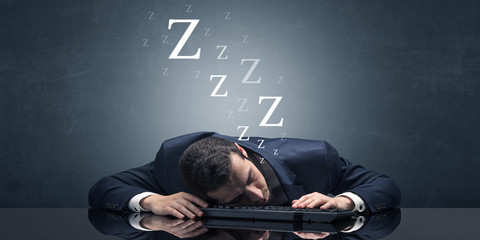 Young businessman fell asleep at the table on his keyboard concept