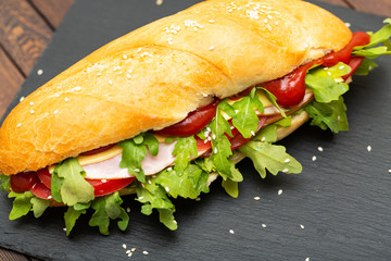 Sandwich with ham, cheese, tomatoes, sauce and salad