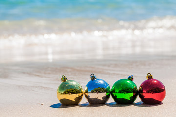 Obraz premium Four christmas multicolored decoration balls on seashore on Phuket island, Thailand - travel X-mas and New Year holidays and vacation in tropics