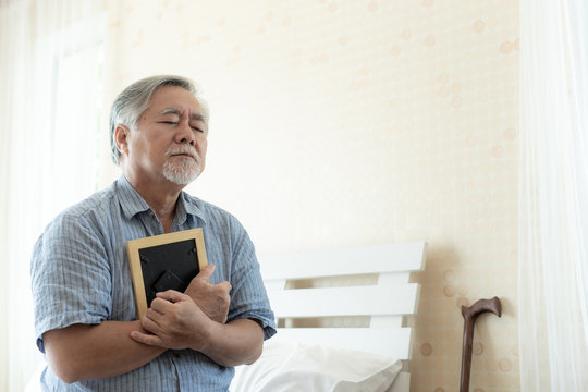 Senior man unhappy is crying, hugging the image of the deceased wife, remember his wife lover - senior sadly concept