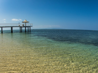 A Long Pier over a Tropical Blue Clear Sandy Beach with No Clouds on Clear Day in Ishigaki, Okinawa Japan