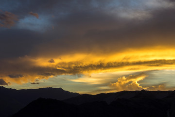 bright colorful sunset sky over dark silhouettes of mountains