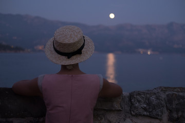 Girl watching the ocean / sea horizon with a Moon rise.