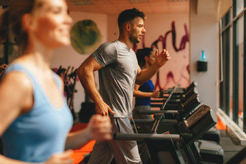 Young man warming up on treadmill at gym